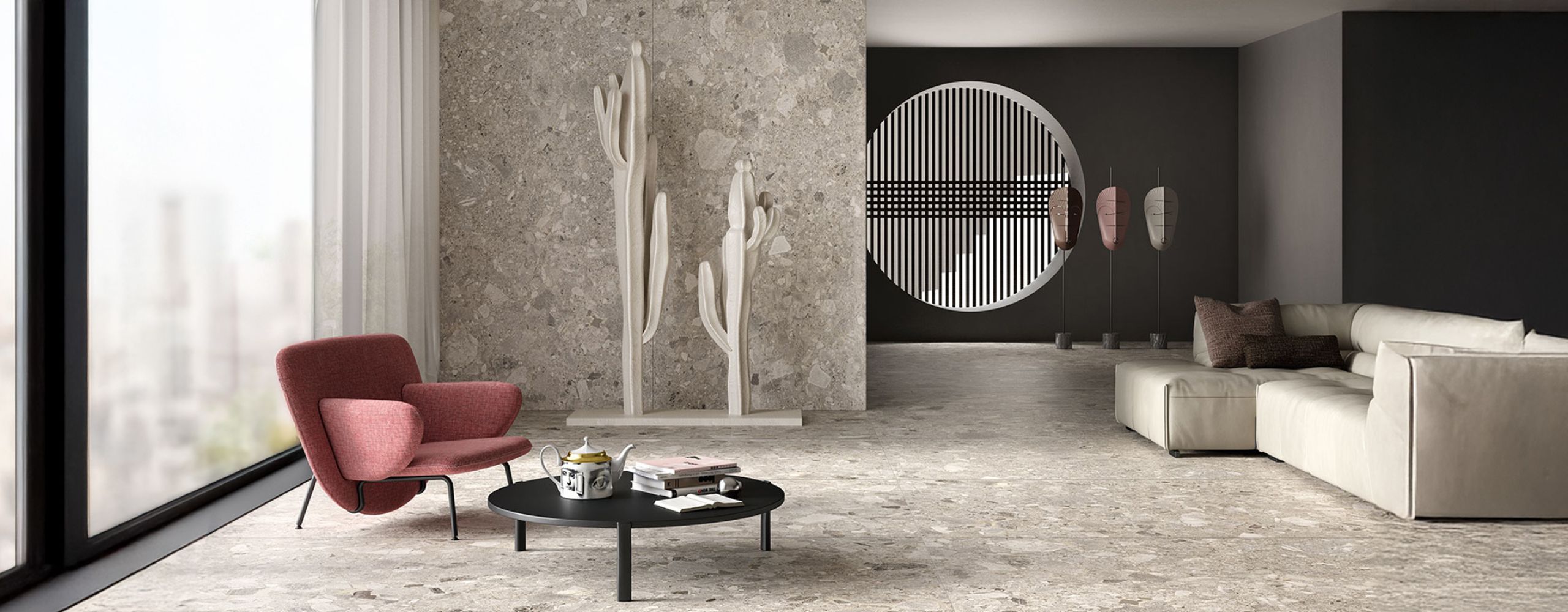 Wohnraum mit Boden- und Wandfliesen in Terrazzo-Optik, rotem Sessel und hellem Sofa